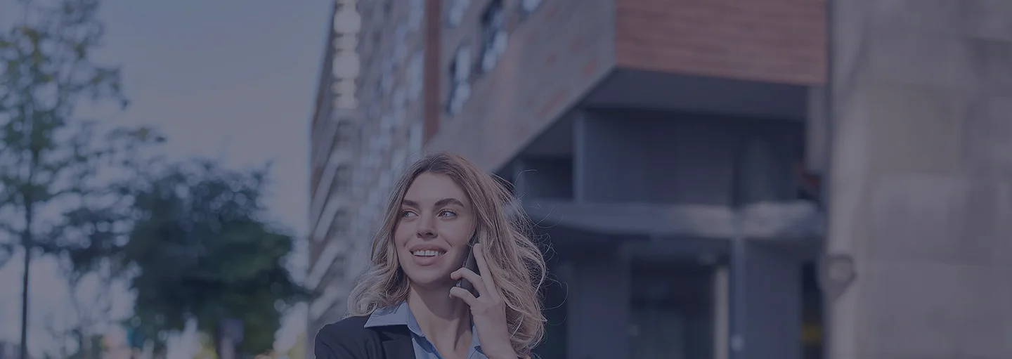 Nő telefonál egy irodaépület előtt